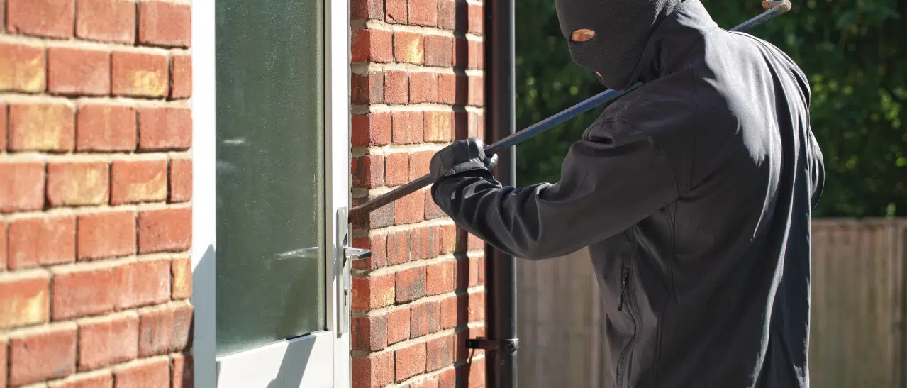 Einbrecher öffnet mit Brecheisen gewaltsam eine alte Eingangstür, um in Wohnung einzudringen.