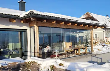 Flexible Glasschiebetüren unter Dachvorsprung bieten kostengünstige Alternativen zu einem Wintergarten für eine grüne Oase im Haus.