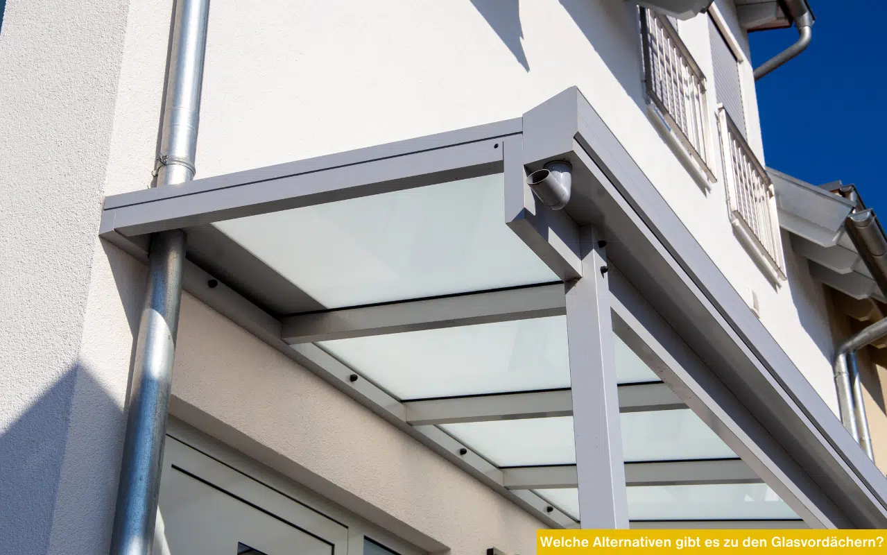 Ein modernes Aluminium-Vordach mit weißem Glas und integriertem Regenabfluss an einer Hauswand.
