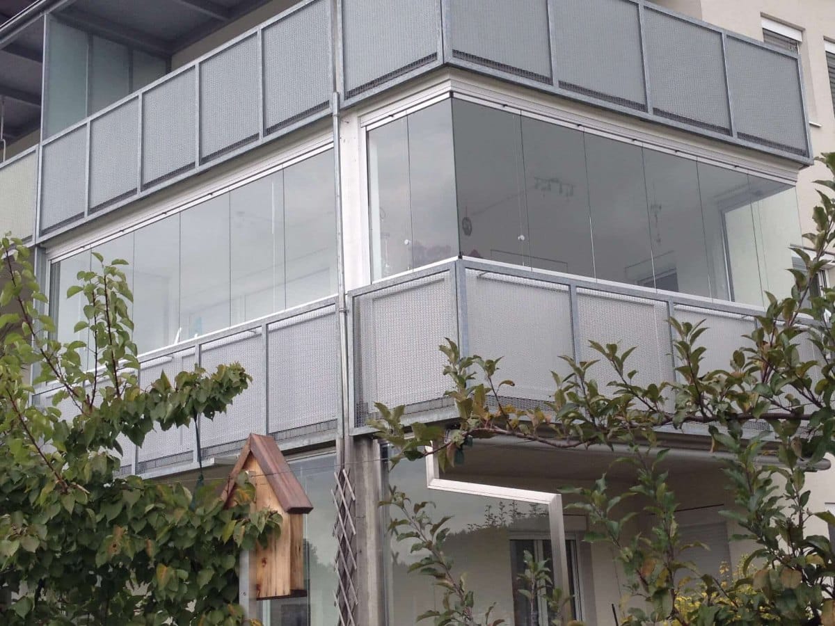 Balkonverglasung mit Schiebe- und Faltfenstern an den Balkonen eines Wohnhauses