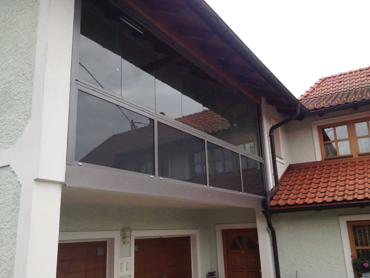 Balkonverglasung unter dem Dachvorsprung eines Hauses mit Ziegeldach