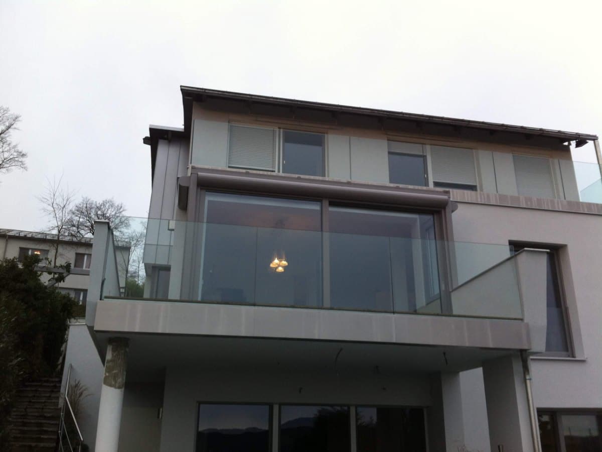 Verglaster Balkon als kleiner Wintergarten mit Glasgeländer an einem modernen Haus