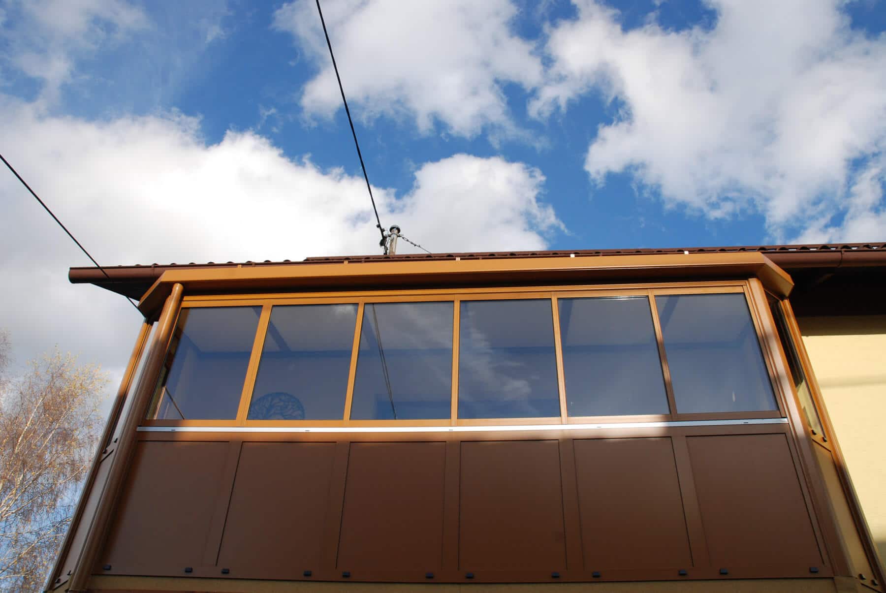 Balkonverkleidung ockerbraun mit Glas-Faltelementen