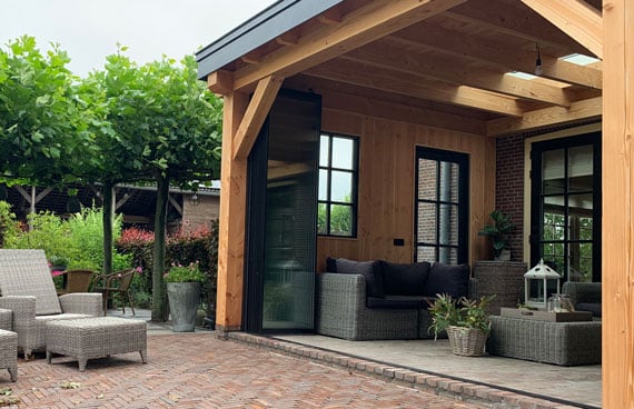 Bedienung Glasfaltwand Sunflex SF 35 an einer modernen Holz-Terrassenüberdachung mit Blick auf den Garten.