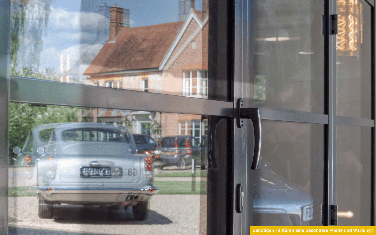 Benötigen Falttüren eine besondere Pflege und Wartung? Nahaufnahme moderner Glas-Falttür mit Griff, Symbolbild für Reinigung und Pflegehinweise.
