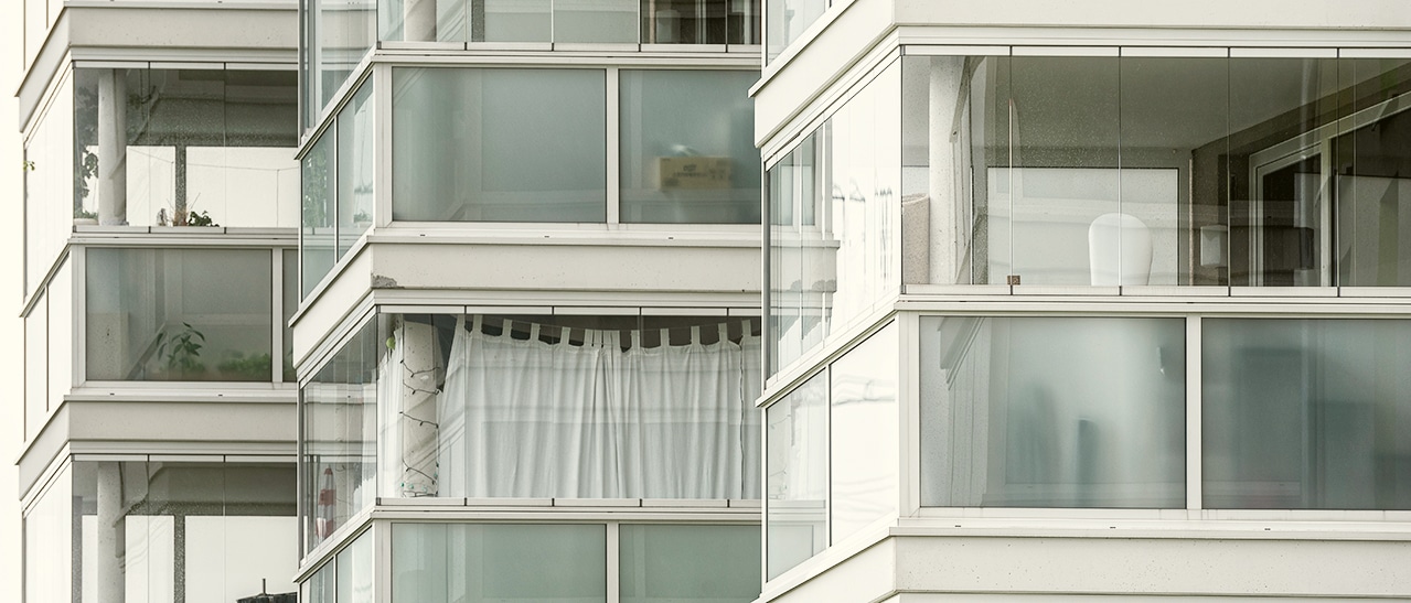 Moderne Wohnanlage mit Balkon- und Wintergartenverglasungen, die teilweise mit blickdichtem Milchglas ausgestattet sind.