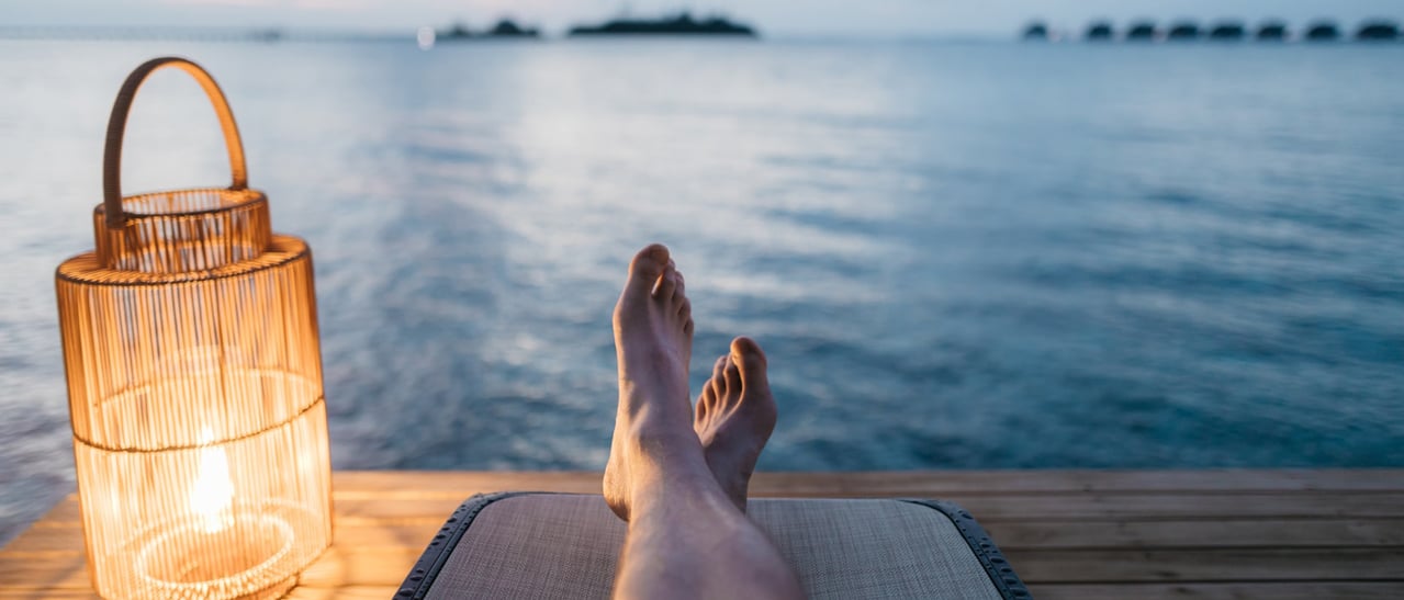 Betriebsurlaub Sommer 2020 bei Fenster-Schmidinger symbolisiert Ruhepause am Meer mit Abendstimmung und warmem Laternenlicht.