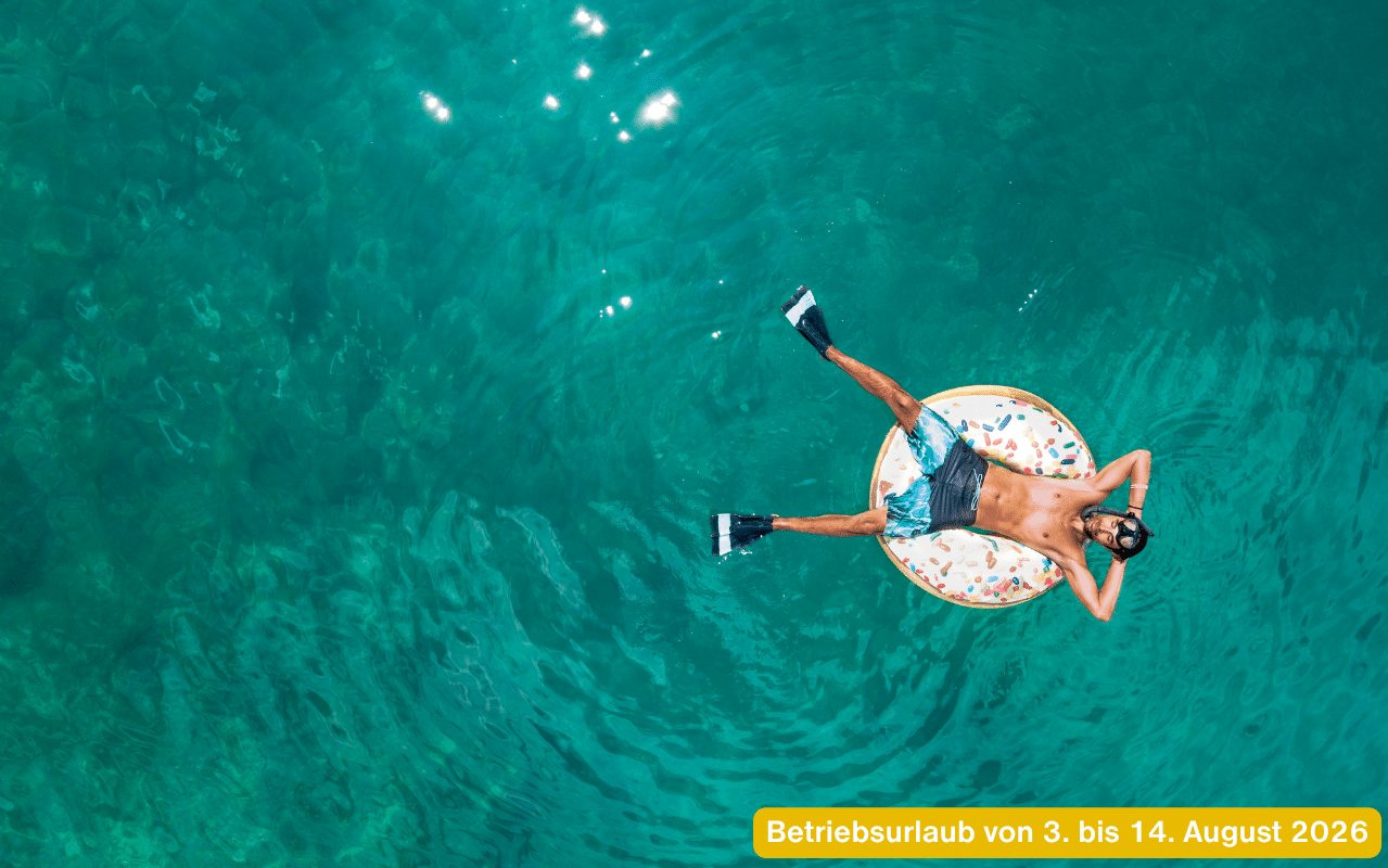 Betriebsurlaub von 3. bis 14. August 2026 Schwimmer auf Luftmatratze im türkisen Meer