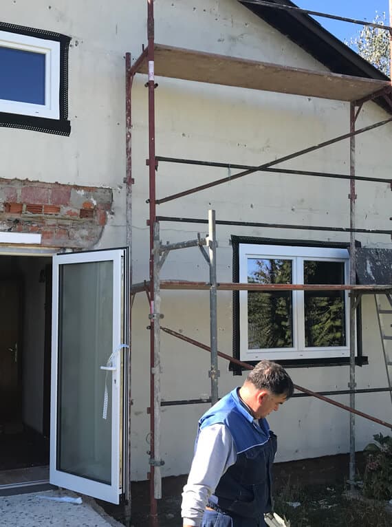 Christkindl-Aktion Fenster-Schmidinger zeigt den Fenstertausch an einer Fassade mit Gerüst und Monteur während der sozialen Sanierungsaktion
