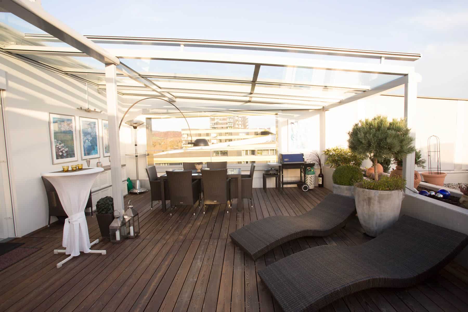 Dachterrasse mit einer Glasüberdachung und seitlichem Windschutz aus Glas