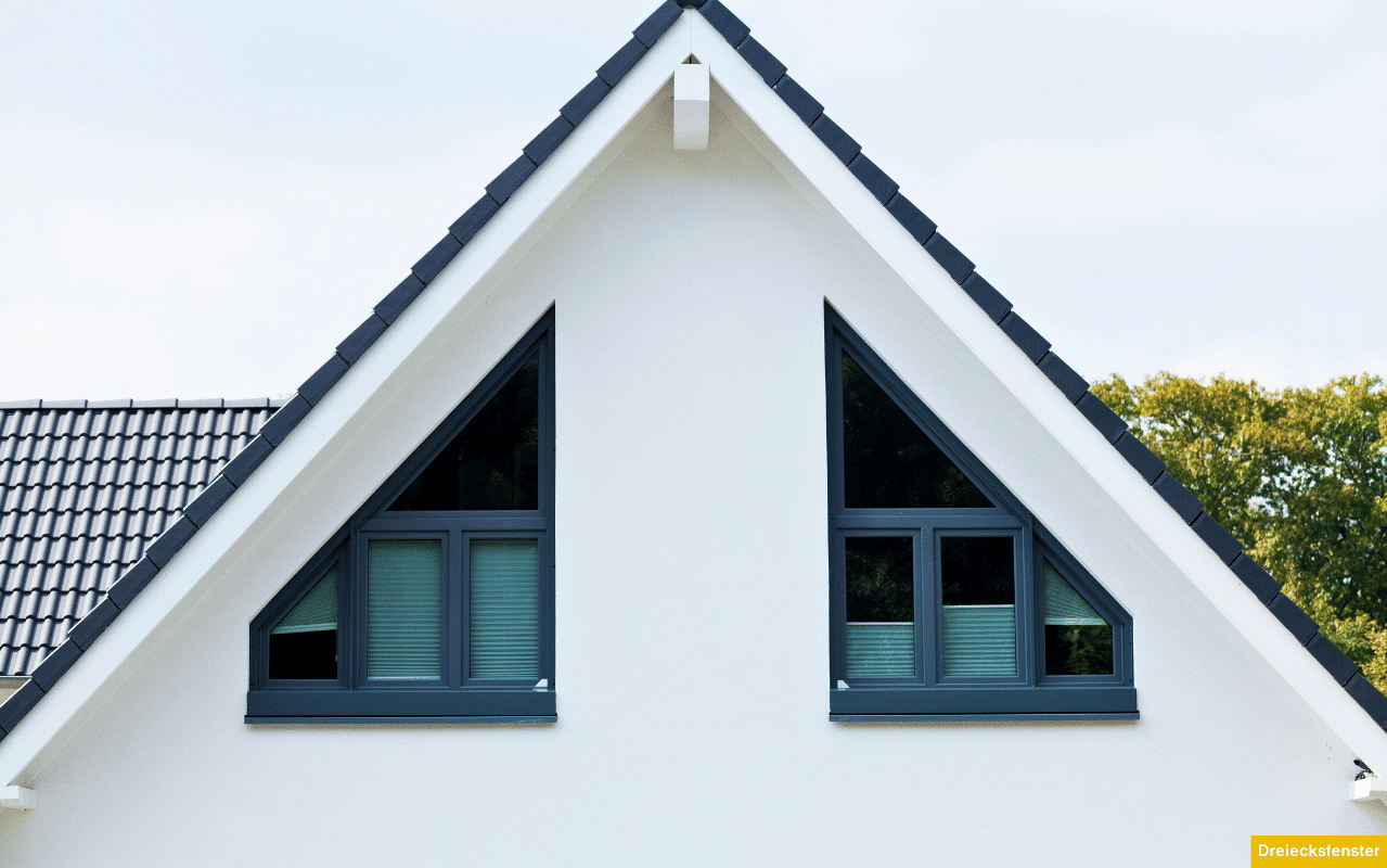 Fenster in Dreiecksform eingebaut in Dachschrägen eines Wohnhauses, dunkelgraue Rahmen heben sich vom weißen Putz ab.