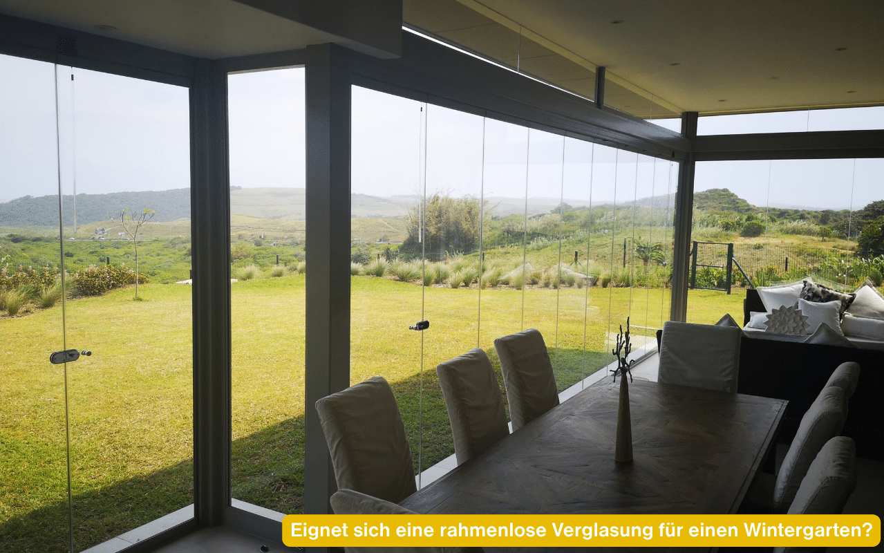 Eignet sich eine rahmenlose Verglasung für einen Wintergarten? Blick aus einer verglasten Terrasse mit Klarglas ins Grüne