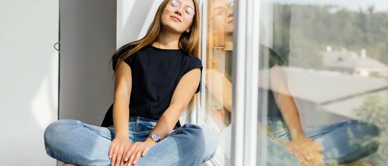 Eine junge Frau in Steyr genießt die neuen Fenster von Fenster-Schmidinger, die Wärme im Winter und Schutz vor Sommerhitze bieten.