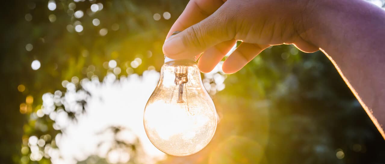 Hand hält Glühbirne im Sonnenlicht Symbol für Energieideen Energiesparmesse Gramastetten