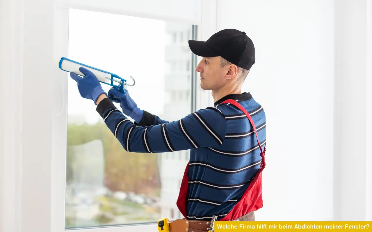 Ein Handwerker trägt mit einer Silikonpistole Dichtungsmasse am Rahmen eines weißen Kunststofffensters auf.