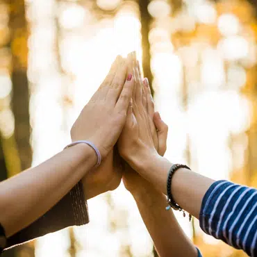 Mehrere Hände treffen sich zum High-Five, symbolisieren die Verbundenheit mit lokalen Firmen und betonen die Bedeutung energieeffizienter Fenster.