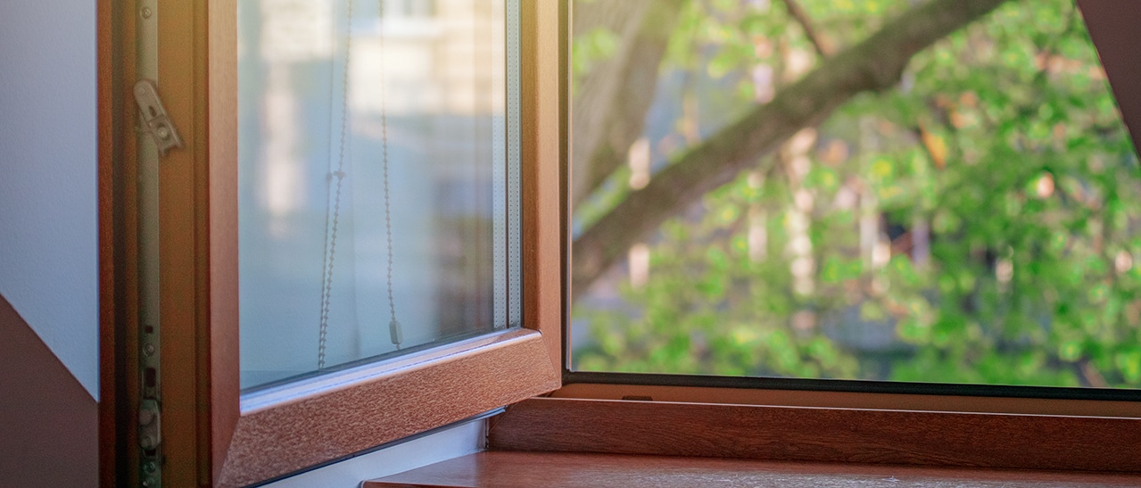 Geöffnetes Fenster in Holzoptik mit Blick ins Grüne, verleiht dem Raum natürliche Wärme und harmoniert mit dem Außenbereich.