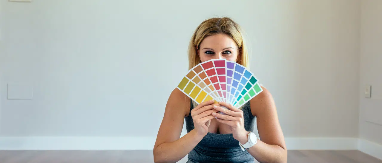 Junge Frau hält RAL-Farbfächer, begeistert von der Fensterfarbe RAL 5007 Brillantblau.