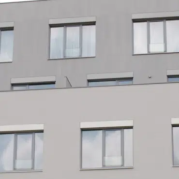 Das Bild zeigt die Fassade eines modernen Gebäudes mit mehreren Fenstern in der Farbe RAL 7001 Silbergrau. Die klaren Linien und die dezente Farbgebung unterstreichen den modernen, urbanen Stil des Hauses.