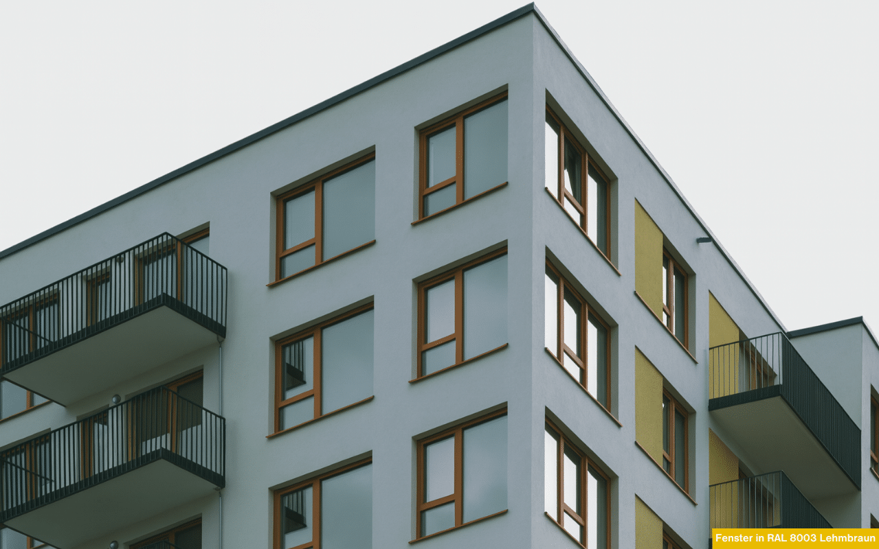 Abgebildet ist ein modernes Mehrparteienhaus mit klarer Linienführung. Die Fensterrahmen in Lehmbraun setzen warme Akzente zur kühlen Fassade und betonen das architektonische Gleichgewicht von Farbe und Form.