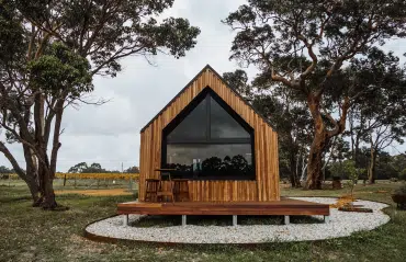 Kleines modernes Holzhaus mit Fenstern in RAL 8019 Graubraun, inklusive Standardrechteckfenstern und verschiedenen Fensterformen.