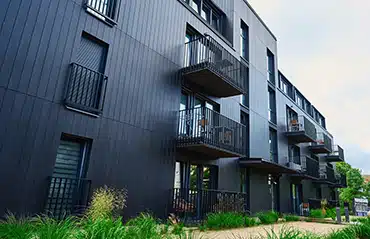 Mehrparteienhaus mit Holzfassade und stilvollen Fenstern in RAL 9005 Tiefschwarz – beliebte Farbe für moderne Architektur.