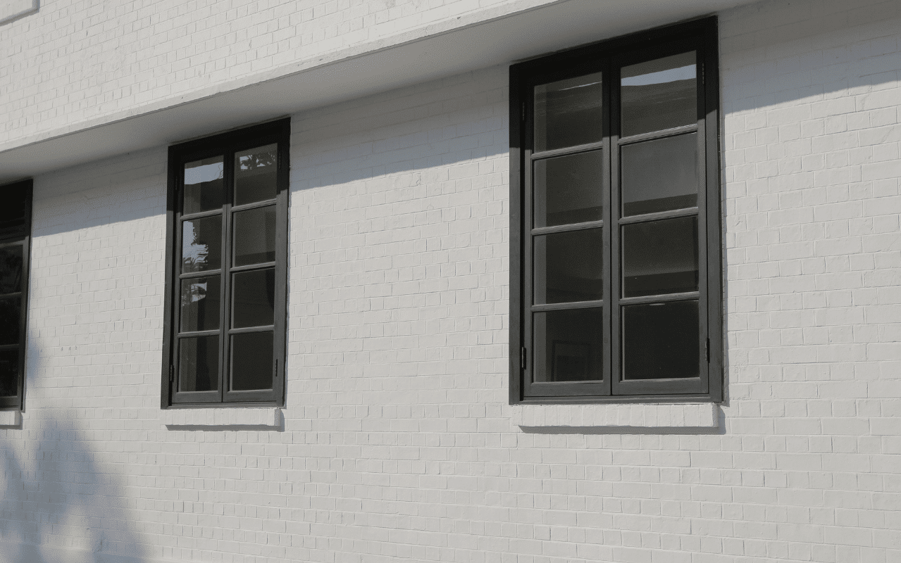 Fenster in RAL 9011 Graphitschwarz mit Sprossen betonen den architektonischen Stil und wirken elegant auf heller Ziegel-Fassade.