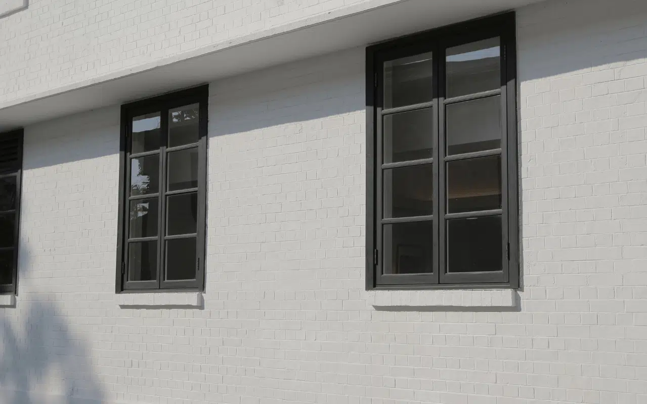 Fenster in RAL 9011 Graphitschwarz mit Sprossen betonen den architektonischen Stil und wirken elegant auf heller Ziegel-Fassade.