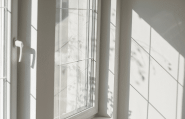 Fenster in RAL 9016 Verkehrsweiß in heller Zimmerecke mit Sprossen und Sonnenlicht