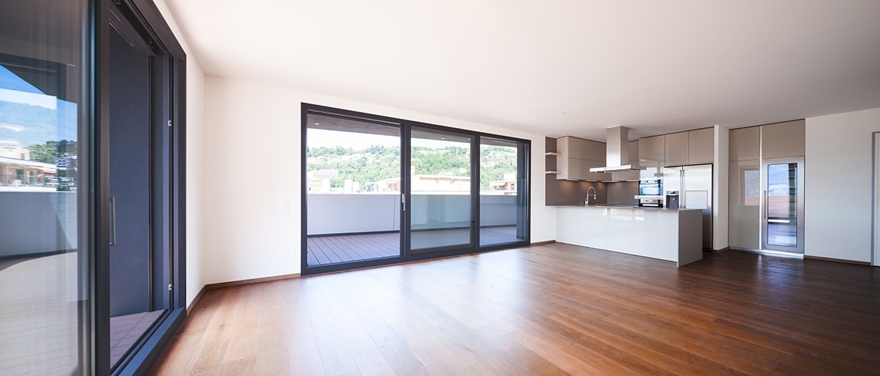 Abgebildet ist ein heller Wohn- und Küchenbereich mit anthrazitfarbenen Fenstern. Die dunkle Folierung sorgt für einen modernen Akzent und fügt sich harmonisch in das minimalistische Interieur ein.