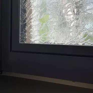 Detailansicht eines Fensters mit Delta Weiß, Aluminiumrahmen und Ornamentglas im Schauraum von Fenster-Schmidinger, Oberösterreich