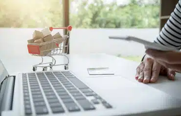 Finger navigiert Laptop, um Fenster online kaufen; vergleicht Online- und stationären Fensterhandel.