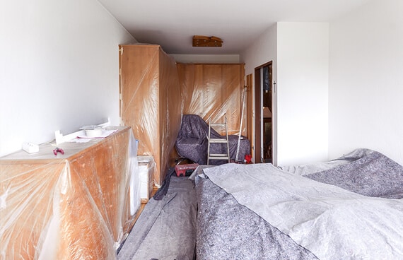 Vorbereitung für die Fenstermontage in Linz durch sorgfältiges Abdecken der Möbel mit Schutzfolie und Malervlies.