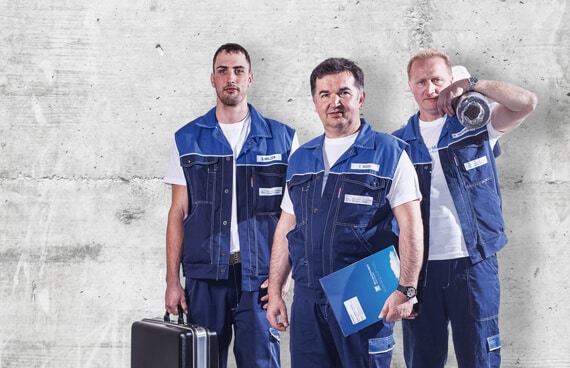Fenstermonteure in Arbeitskleidung posieren mit Werkzeug und Materialien, bereit für den Einsatz bei Sanierungsarbeiten.