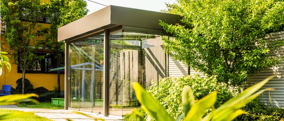 Schaugarten mit Wintergarten als freistehender Glasanbau mit Flachdach zwischen Bäumen