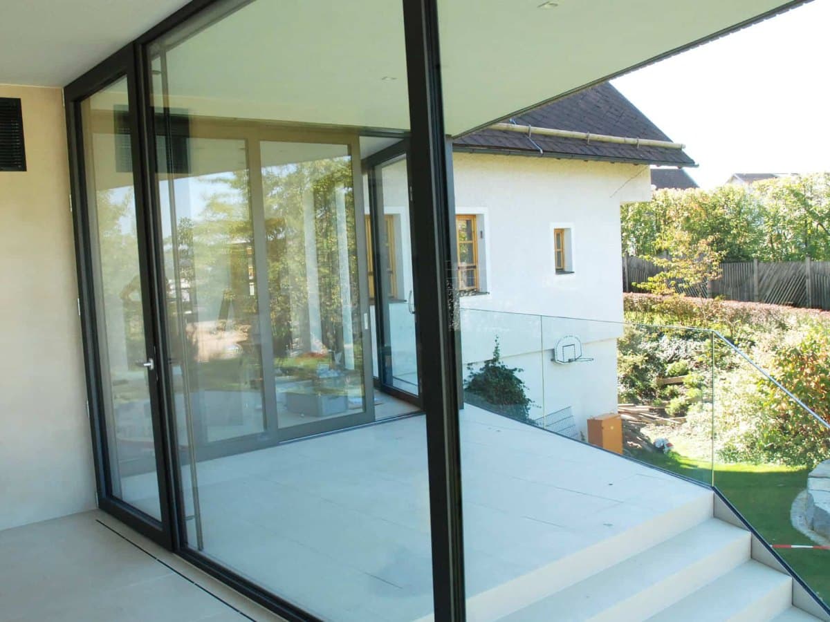 Bodentiefe Terrassentür mit großer Aluminium-Fixverglasung nach einer Fenstervergrößerung, Blick auf die Terrasse