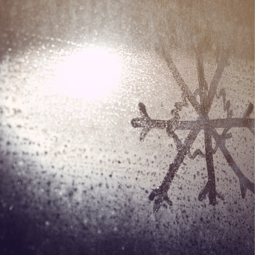 Detailansicht einer Schneeflocke aus Eiskristallen am Fensterglas. Hinweis auf den jährlichen Fenstercheck im Frühling nach der Kälteperiode.