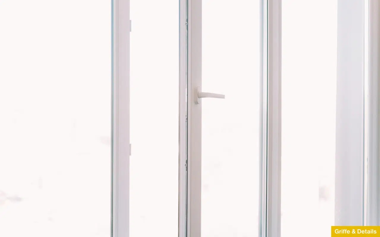 Detailaufnahme eines modernen Fenstergriffs an einem hellen Profil - Fokus auf die Abstimmung von Griff und Rahmenfarbe.