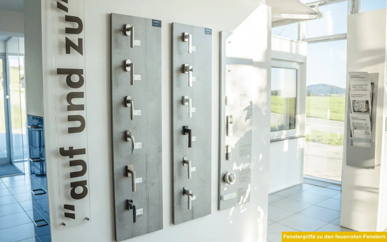 Fenstergriffe zu den feuerroten Fenstern in moderner Ausstellung mit verschiedenen Griffmodellen auf Wandpaneelen im Schauraum