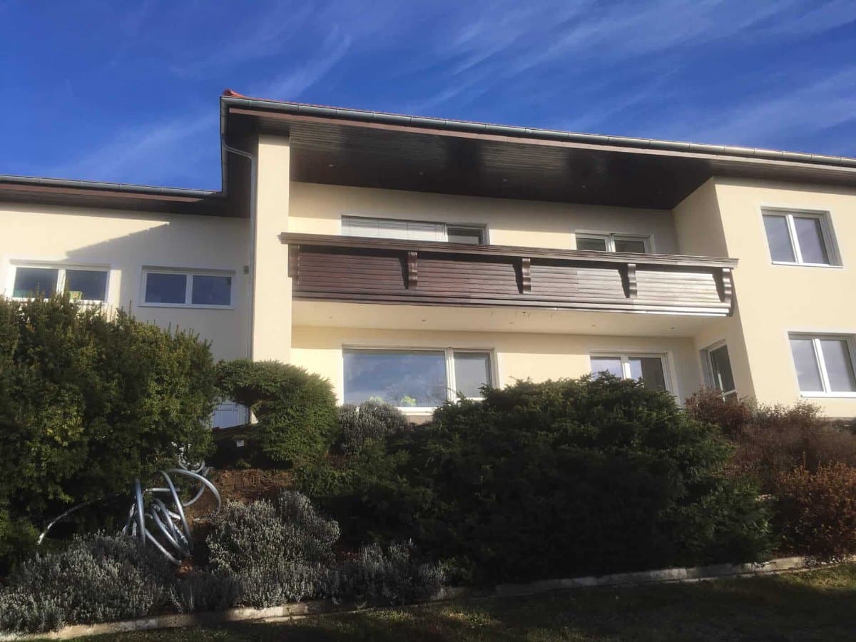 Einfamilienhaus mit neuen weißen Fenstern in beiden Geschoßen und Holzbalkon