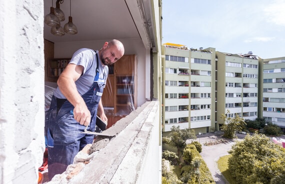 Auf der Baustelle in Linz; Monteur stellt Glattstrich nach Demontage des alten Fensters her für einen sauberen Untergrund beim Fenstertausch.