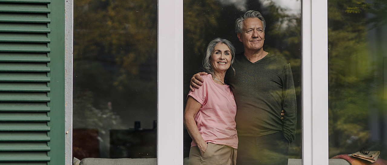 Älteres Familienpärchen steht vor den neuen Fenstern von Fenster-Schmidinger