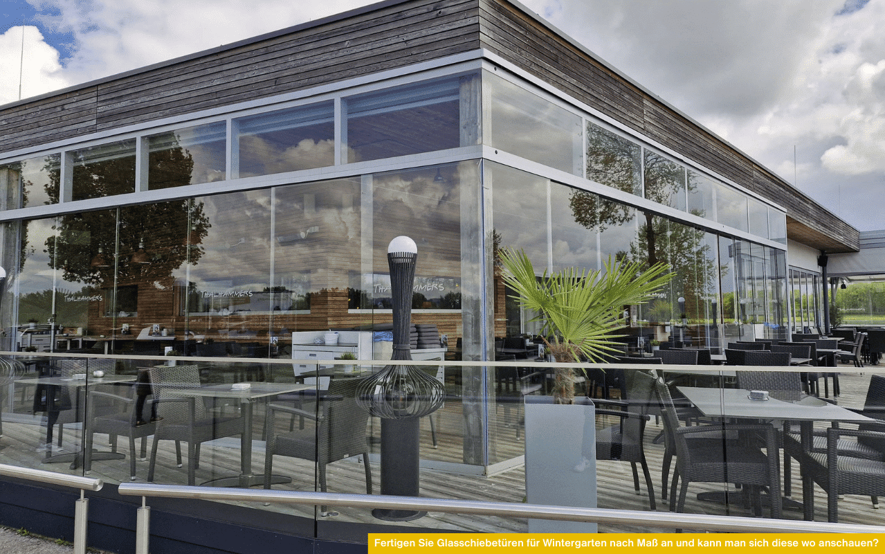 Moderne Wintergartenanlage mit großen Glasfronten und Schiebetüren, davor Terrasse mit Sitzmöbeln und Palmen-Deko.