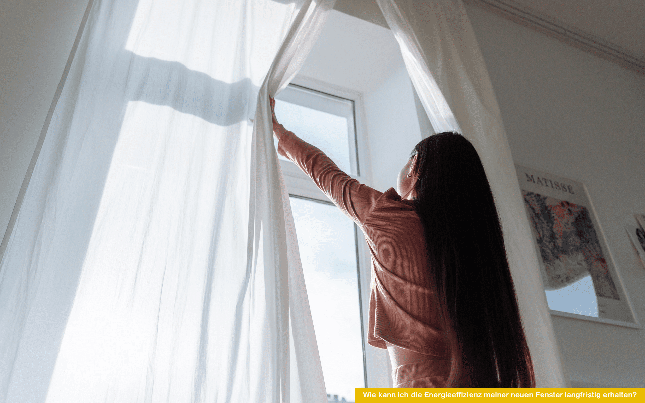 Frau öffnet weiße Gardine vor Fenster - wie kann ich die Energieeffizienz meiner neuen Fenster langfristig erhalten.