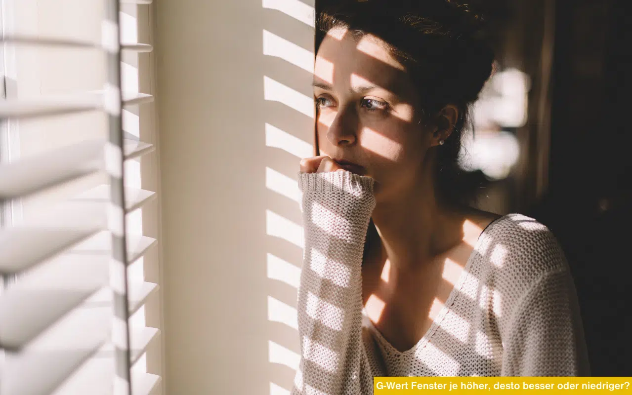 Eine junge Frau blickt nachdenklich durch ein Fenster, während Jalousien ein Streifenmuster aus Licht und Schatten erzeugen.