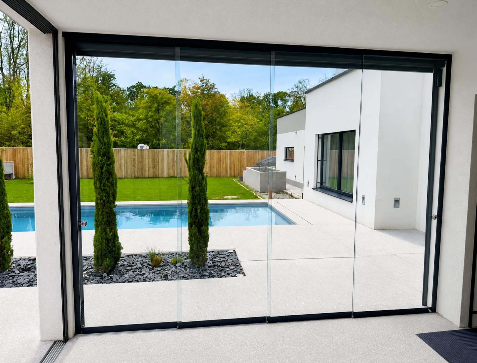 Blick durch die Ganzglas-Schiebetüren auf Pool und Garten