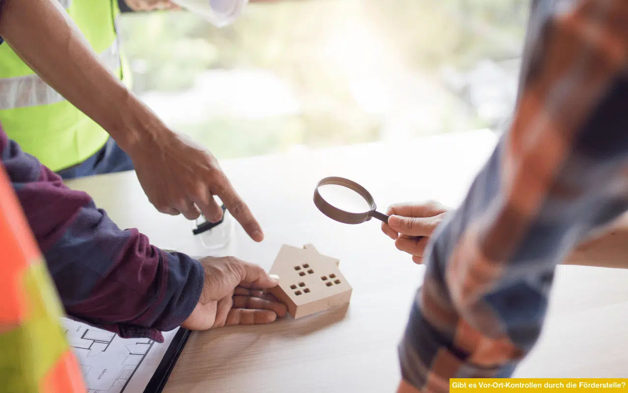 Das Bild zeigt mehrere Personen bei der Prüfung eines kleinen Hausmodells mit einer Lupe und Bauplänen. Es symbolisiert eine mögliche Vor-Ort-Kontrolle der Förderstelle zur Überprüfung eingereichter Sanierungsmaßnahmen und Betrugsbekämpfung.