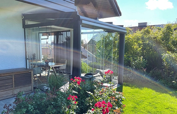 Glasschiebetüren Wintergarten nach Maß vom Händler mit moderner Verglasung, Aluminiumrahmen und Blick in den gepflegten Garten.
