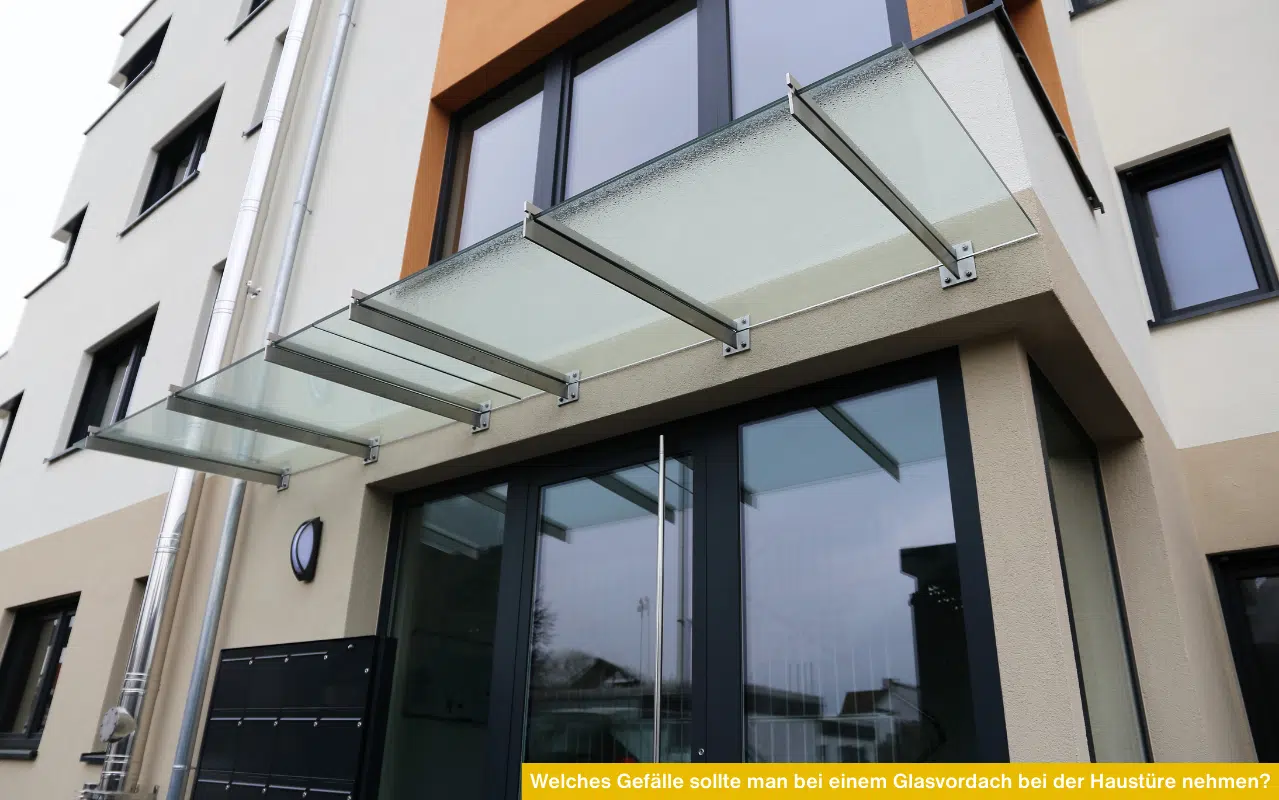 Ein mehrteiliges Glasvordach mit leichter Neigung, montiert mit Metallhalterungen über einem modernen Hauseingang.