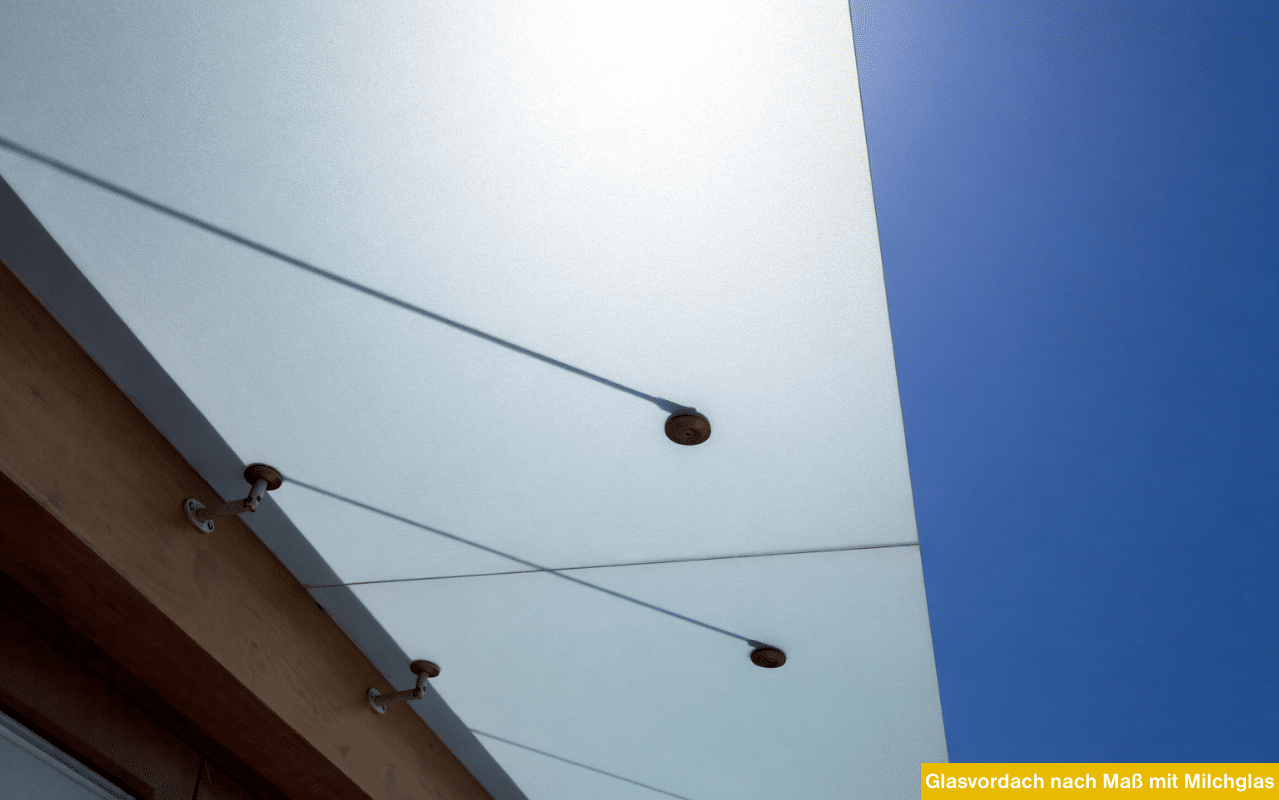 Ein satiniertes Milchglasvordach mit Punktfaltern vor einem strahlend blauen Himmel.